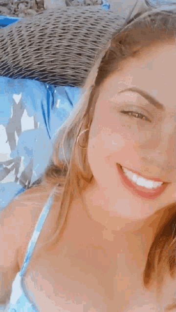 a woman in a bikini is smiling for the camera while laying on a chair .