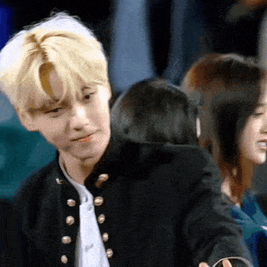 a man in a black jacket is standing next to a woman in a crowd of people .