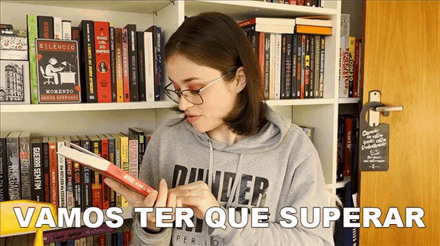 a woman reading a book with the words vamos ter que superar below her