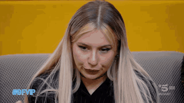 a woman sitting on a couch with the hashtag #gfvip on her face