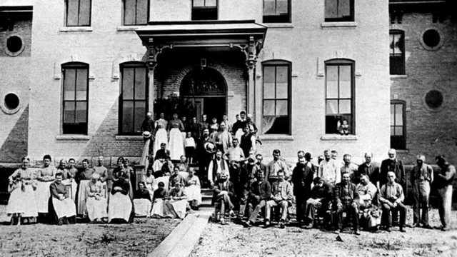 a black and white photo of a group of people standing outside of a building