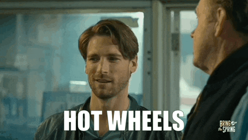 a man is talking to another man with the words hot wheels written on his face