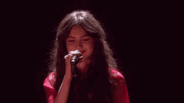 a woman is singing into a microphone on a stage .