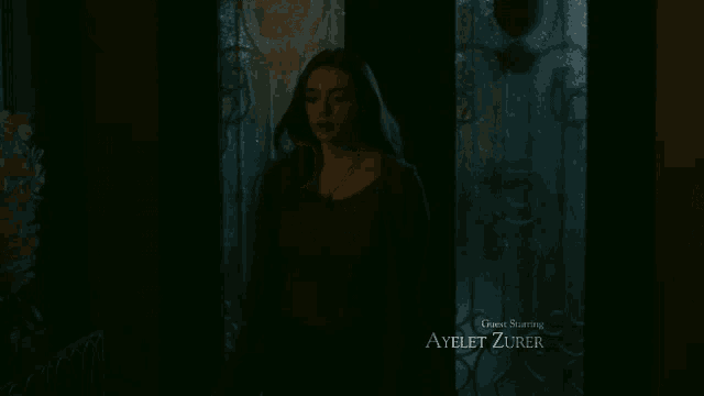 a woman in a dark room with a necklace on