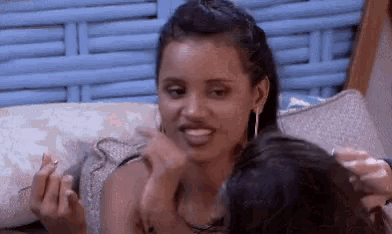 a woman is sitting on a couch with another woman and making a face .