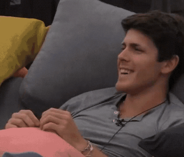 a man is laying on a couch with a pink pillow