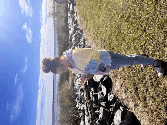 a woman in a tie dye sweatshirt stands in a field