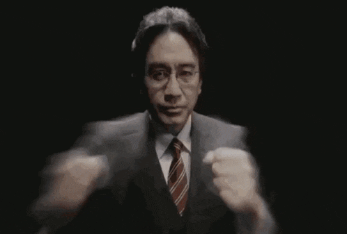 a man in a suit and tie is holding a microphone in his hand in a dark room .