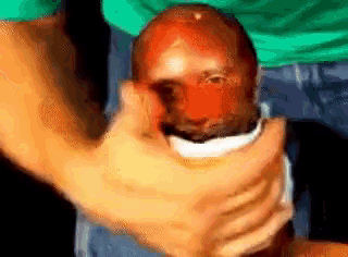 a close up of a person holding a man 's head with a red face .