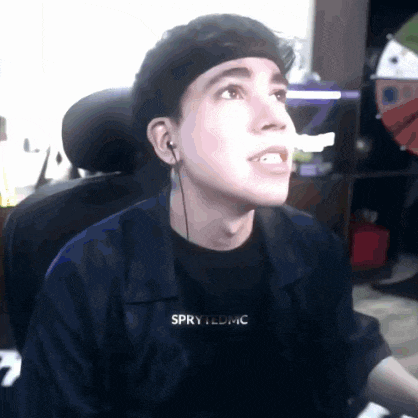 a man wearing headphones and a shirt that says spry ledmc is sitting in a chair