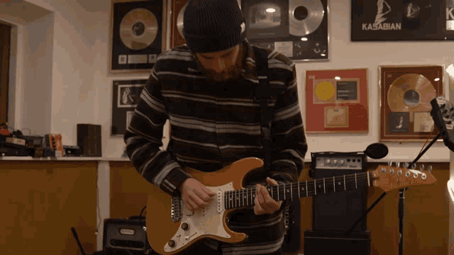 a man playing a guitar in front of a poster that says kasabian on it