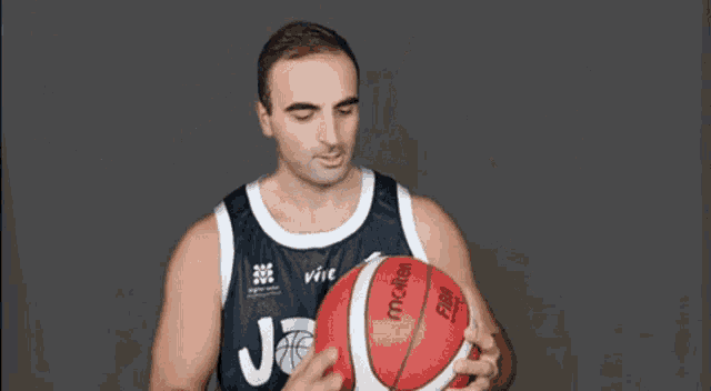 a man in a joea jersey is holding a red basketball