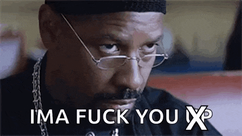 a man wearing glasses and a hat is sitting at a table and saying `` ima fuck you x '' .