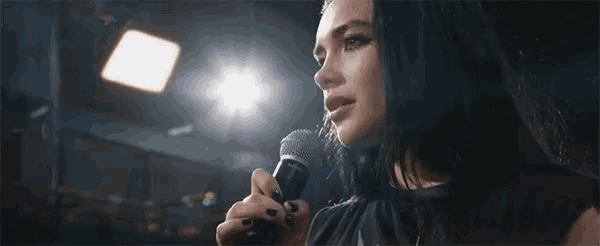 a woman is singing into a microphone on stage .