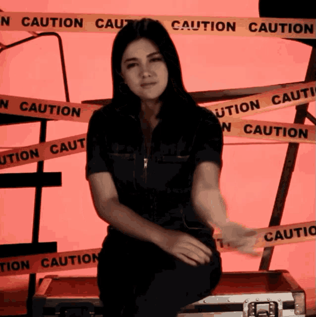 a woman is sitting on a briefcase with caution tape around her