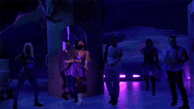 a woman in a purple dress wearing a face mask