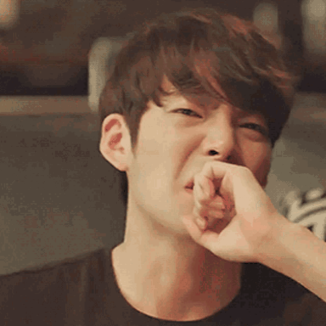 a young man covering his mouth with his hand while smiling
