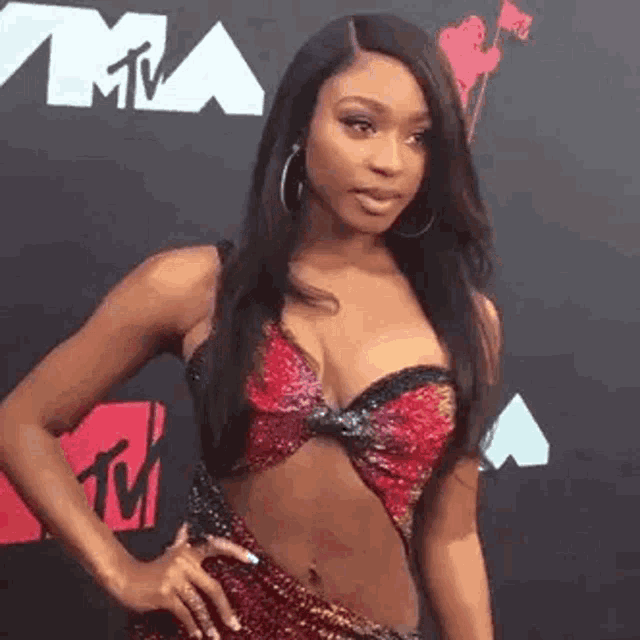 a woman is standing on a red carpet wearing a very revealing dress and hoop earrings .
