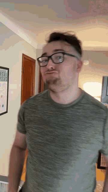 a man wearing glasses and a green shirt is standing in front of a framed poster that says ' i love you '