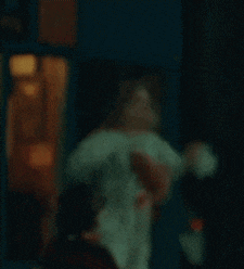 a blurry picture of a clown holding a knife in his hand in a dark room .