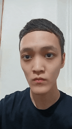 a young man wearing a black t-shirt looks at the camera