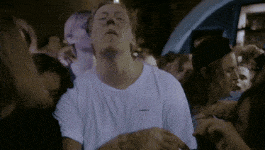 a man in a crowd wearing a white shirt that says carhartt on it