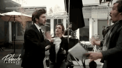 a man in a suit and tie is standing next to a woman in a black jacket with the name roberto duarte on the bottom