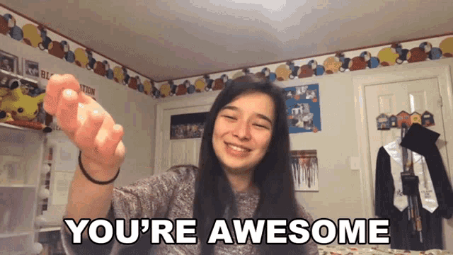 a girl says you 're awesome in front of a wall with balloons