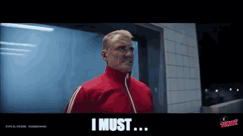 a man in a red jacket says " i must " in a dark room