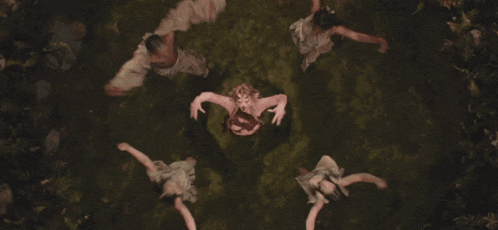 a woman in a pink dress is laying on her back with her arms outstretched