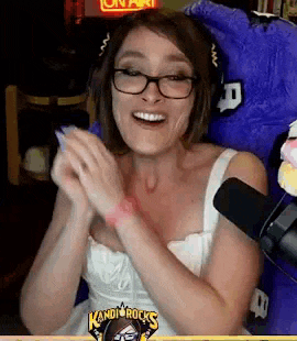 a woman wearing glasses is sitting in front of a microphone and a stuffed animal .