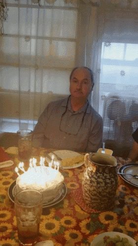 a man sits at a table with a birthday cake
