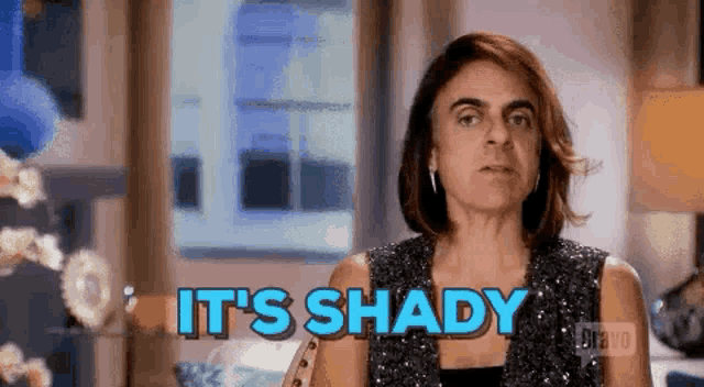 a woman is standing in front of a window with the words `` it 's shady '' written on her face .