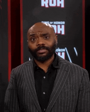 a bald man with a beard is wearing a suit and black shirt
