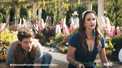 a man and a woman in a garden with a nbc logo on the bottom