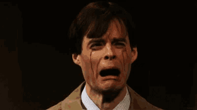a man in a suit and tie is crying with tears coming out of his eyes .