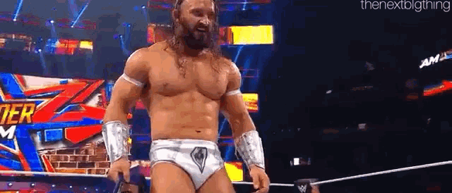 a shirtless wrestler is standing in a ring holding a microphone .