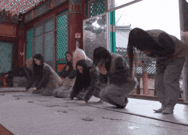 a group of women are kneeling down in a room with a fire extinguisher on the wall