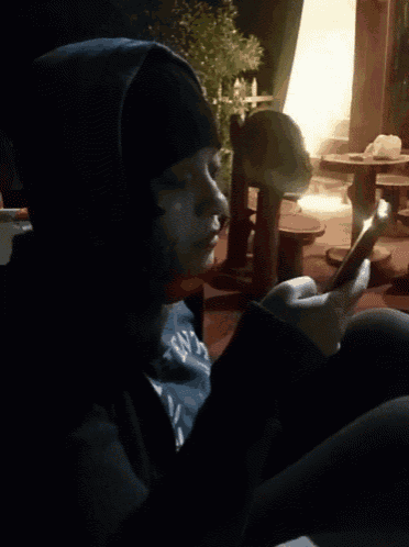 a person in a hooded jacket is looking at their phone