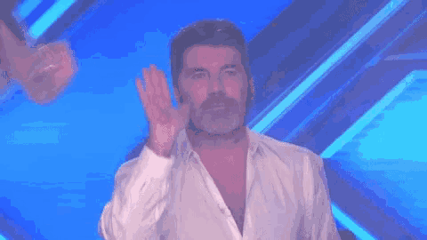 a man in a white shirt is standing in front of a blue background and making a funny face .