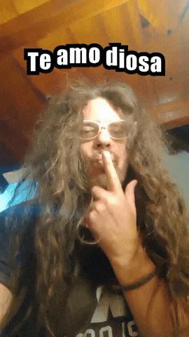 a man with long hair and glasses holds his finger to his lips and says " te amo diosa "