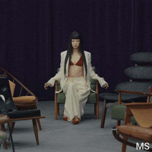 a woman in a red bra is sitting in a chair with the letters ms below her