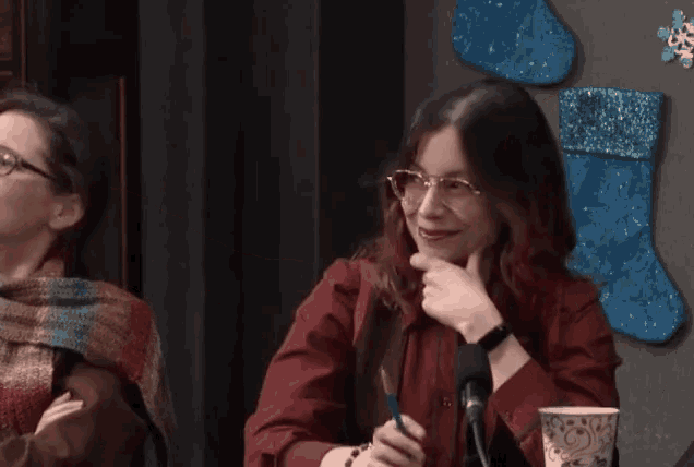a woman wearing glasses is smiling while sitting at a table