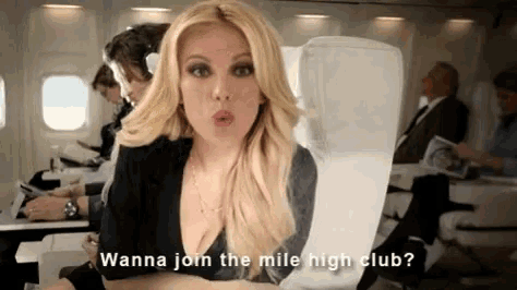 a woman is sitting on an airplane talking about joining a mile high club