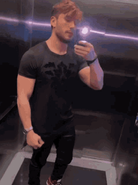 a man in a black shirt is taking a picture of himself in a mirror