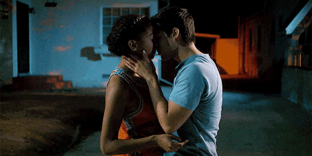 a man and woman kissing in front of a building