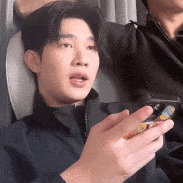 a man in a black jacket is holding a phone with a sticker on it that says ' candy ' on it