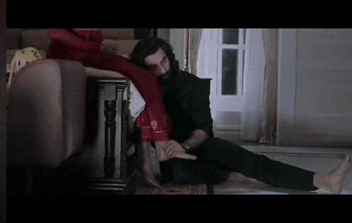 a man is sitting on the floor holding a woman 's foot