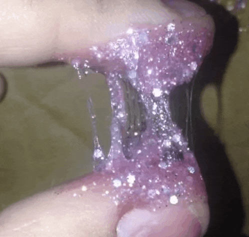 a close up of a person 's hand with purple slime coming out of it .