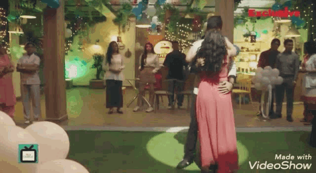 a woman in a pink dress is hugging a man